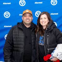 Man and woman standing in front of GV alumni backdrop
